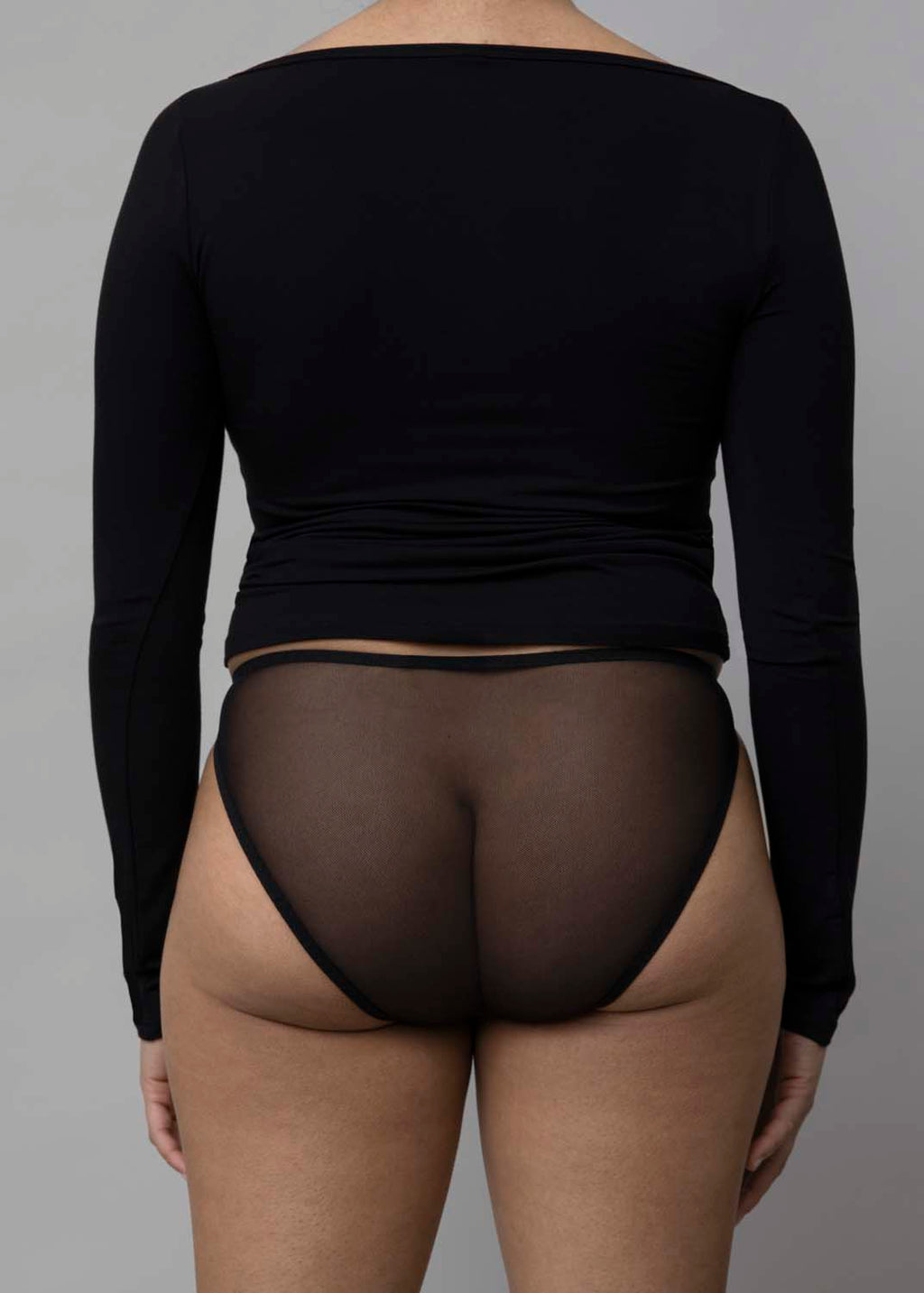 Back view of a model wearing Kye Recline Bateau Long Sleeve, a black bamboo boat neckline long sleeve tee.