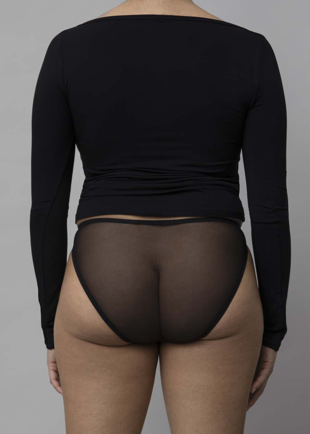 Back view of a model wearing Kye Recline Bateau Long Sleeve, a black bamboo boat neckline long sleeve tee.
