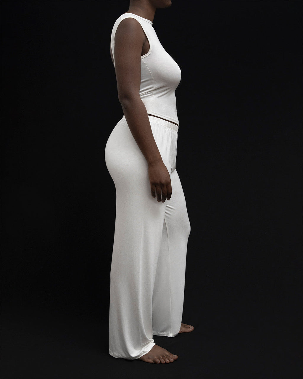 Side view of a model wearing Kye Recline Pant bamboo long pants in white. The breathable bamboo fabric and relaxed fit provide comfort and style, perfect for everyday wear by Kye Intimates.