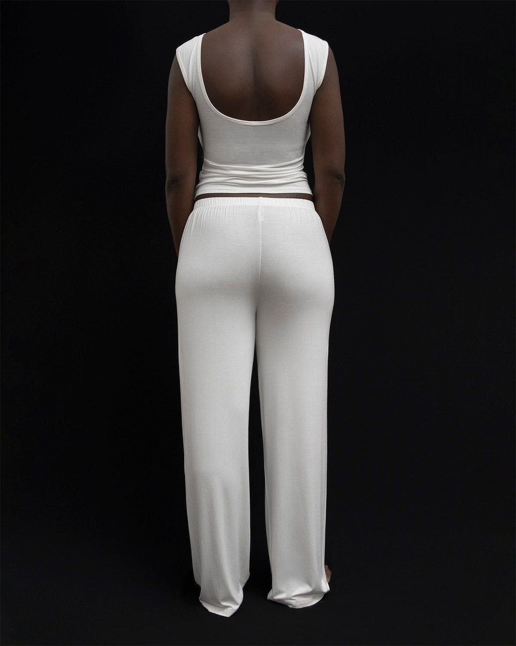 Back view of a model in Kye Recline Pant bamboo long pants in white. The pants feature a comfortable elastic waistband and are made from soft, eco-friendly bamboo fabric, highlighting the quality of Kye Intimates.