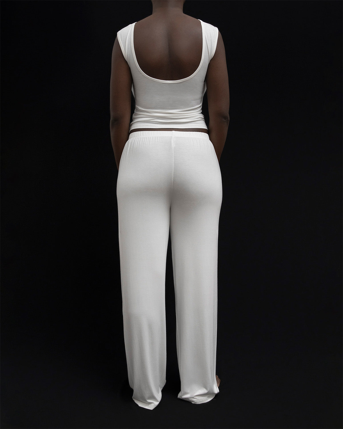 Back view of a model in Kye Recline Pant bamboo long pants in white. The pants feature a comfortable elastic waistband and are made from soft, eco-friendly bamboo fabric, highlighting the quality of Kye Intimates.