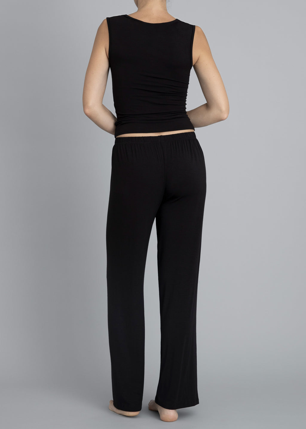 Back view of a model wearing Kye Recline Pant bamboo long pants in black. The pants feature a comfortable elastic waistband and a loose, flowy design, showcasing Kye Intimates’ commitment to comfort and style.
