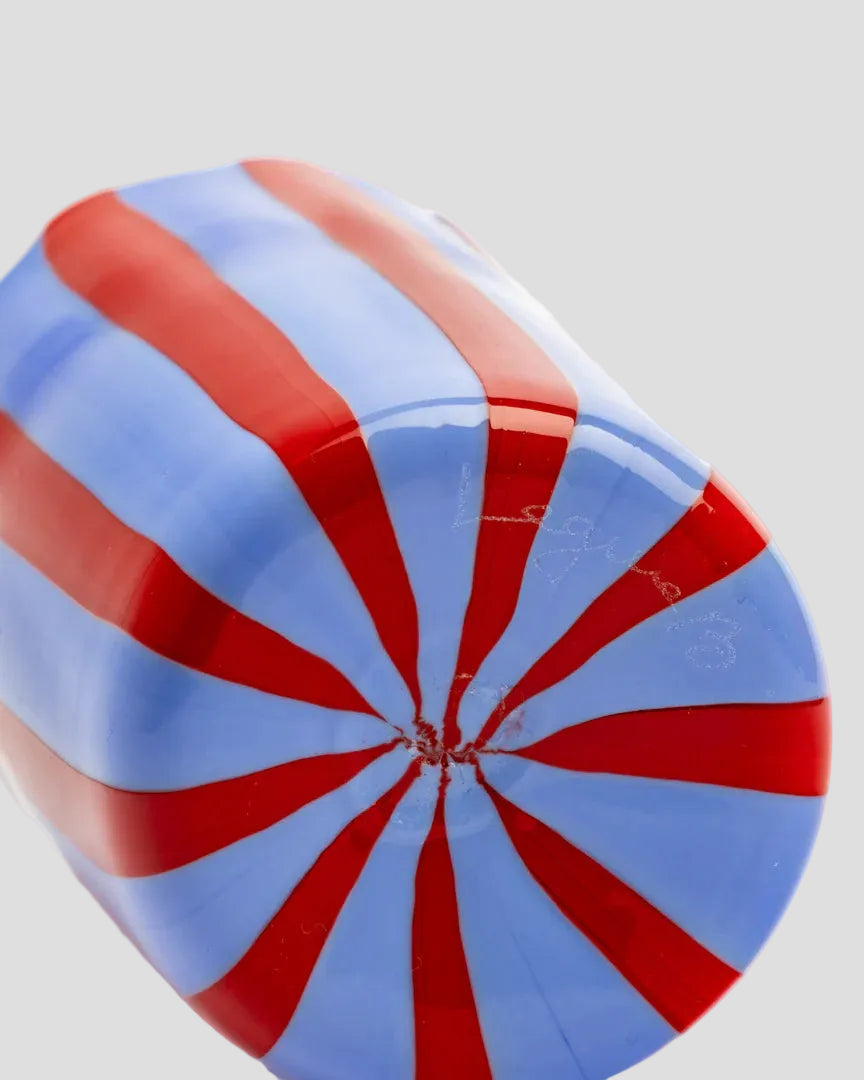 A close-up of a glossy, rounded cylindrical object featuring a red and light blue radial striped pattern, set against a plain white background.