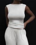 Model wearing Kye Recline Bateau Sleeveless, a white bamboo boat neckline sleeveless tank, paired with white pants.